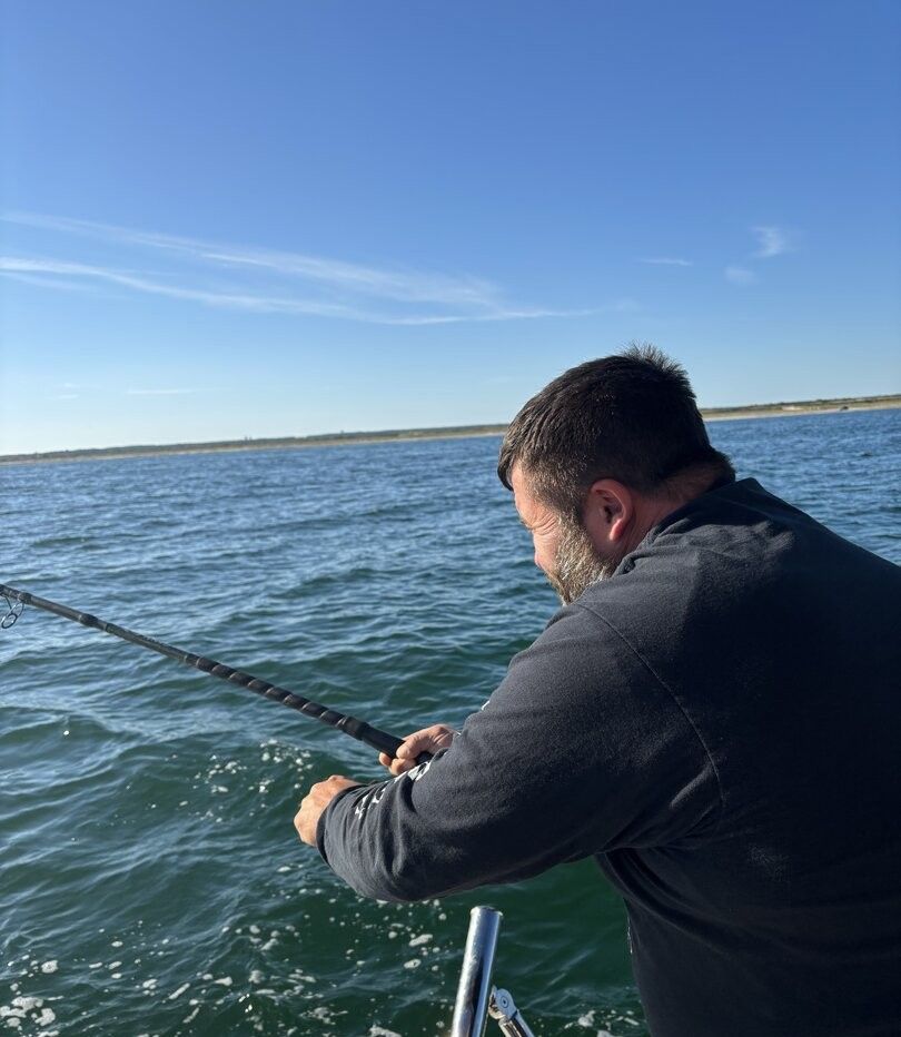 Fishing rod extended over water from boat deck on calm day