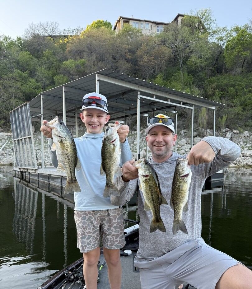 Successful fishing trip showing four caught bass displayed near boat dock