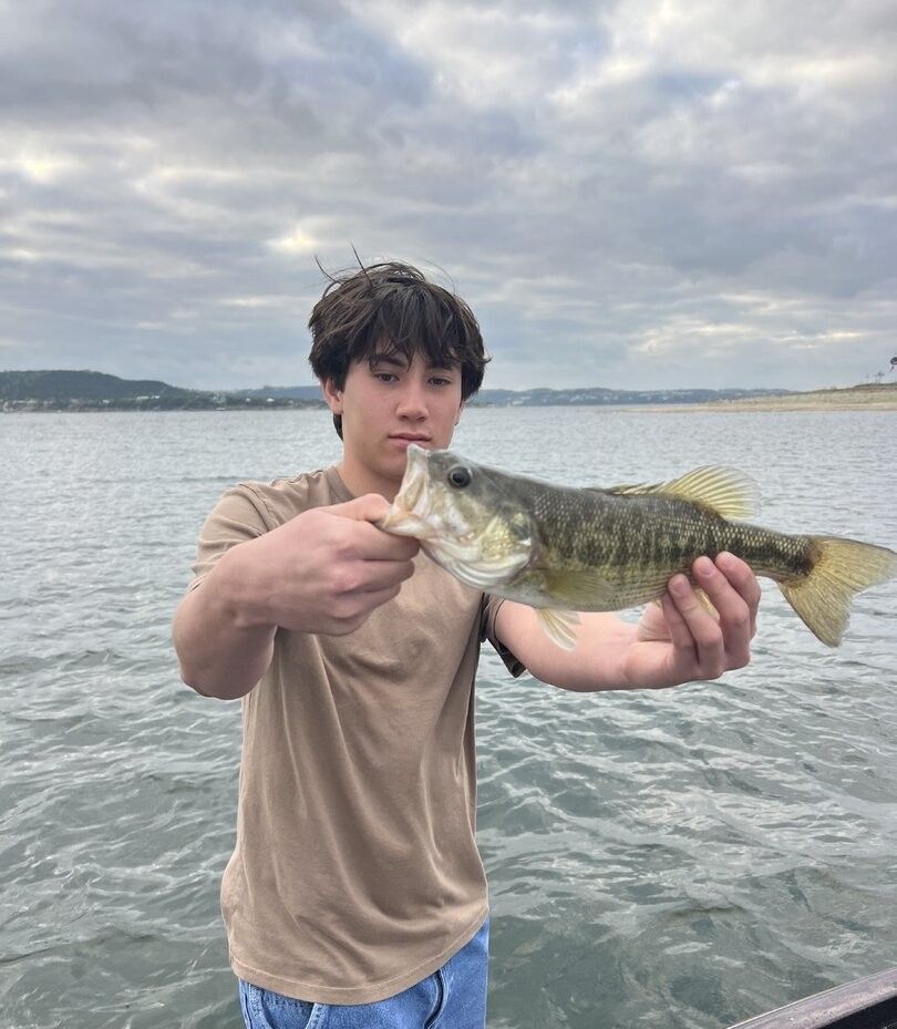 Freshly caught Guadalupe Bass being held over lake water