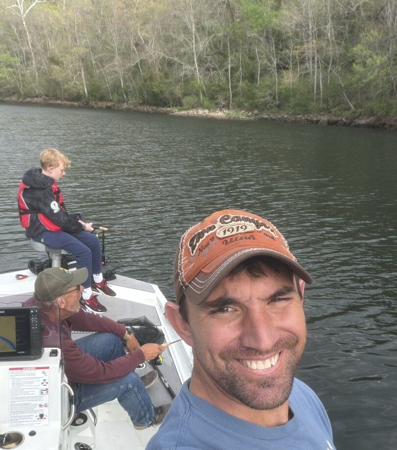 Fishing trip on calm lake with wooded shoreline in background