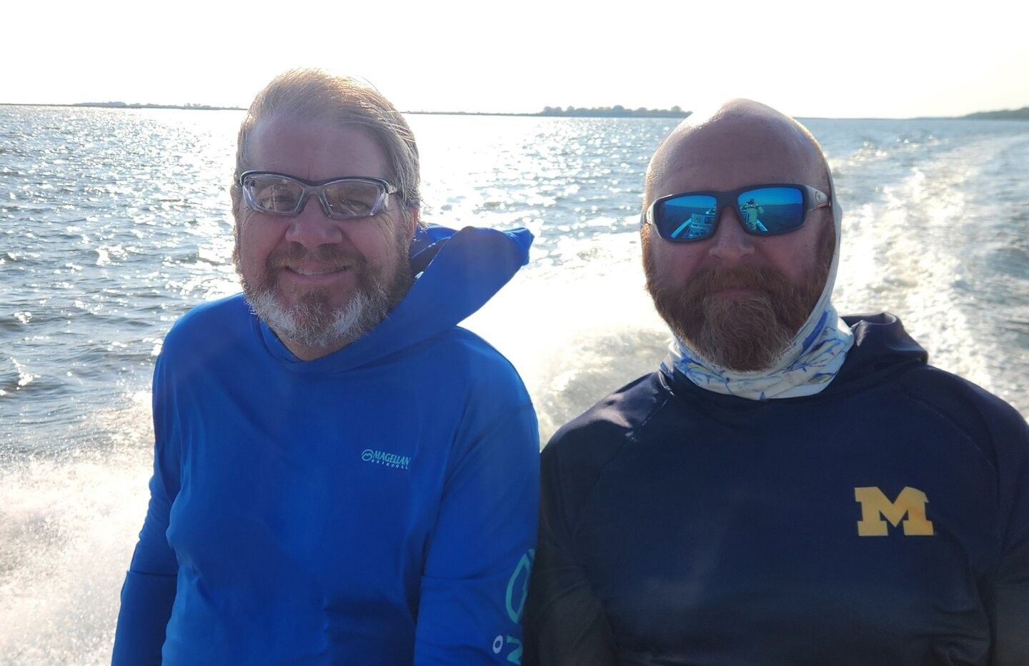 Two people standing together on a boat with water and distant shoreline in background