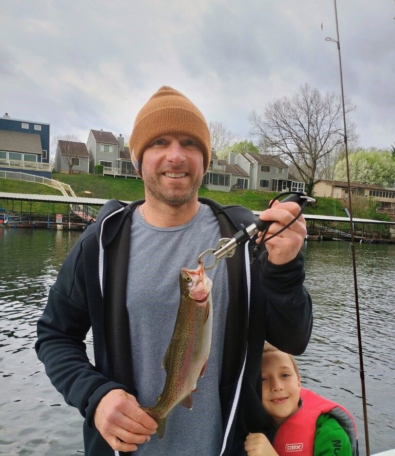 Rainbow trout caught while fishing outdoors on lake with residential homes in background