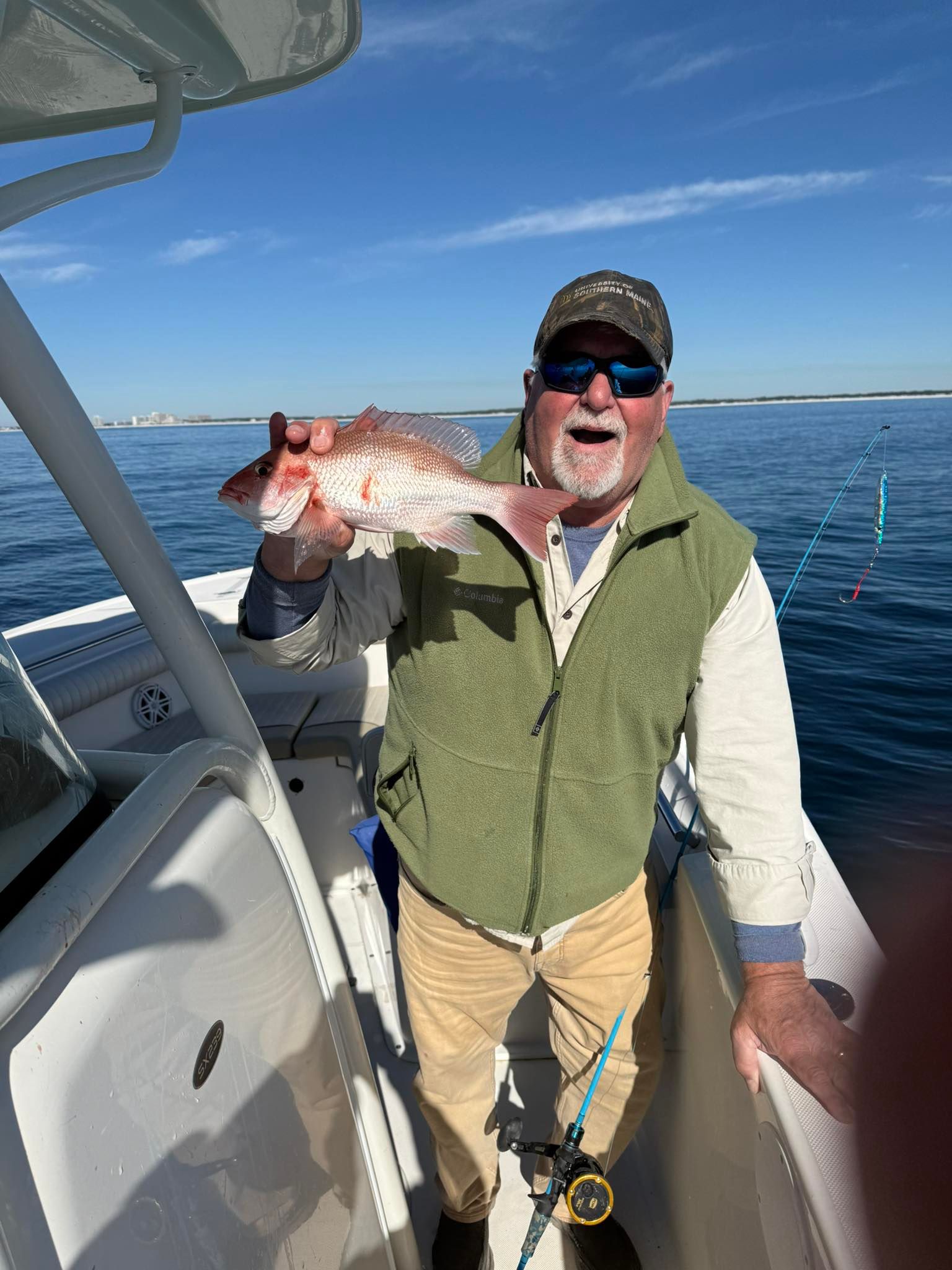 Freshly caught red snapper being displayed on fishing boat deck with ocean waters in background