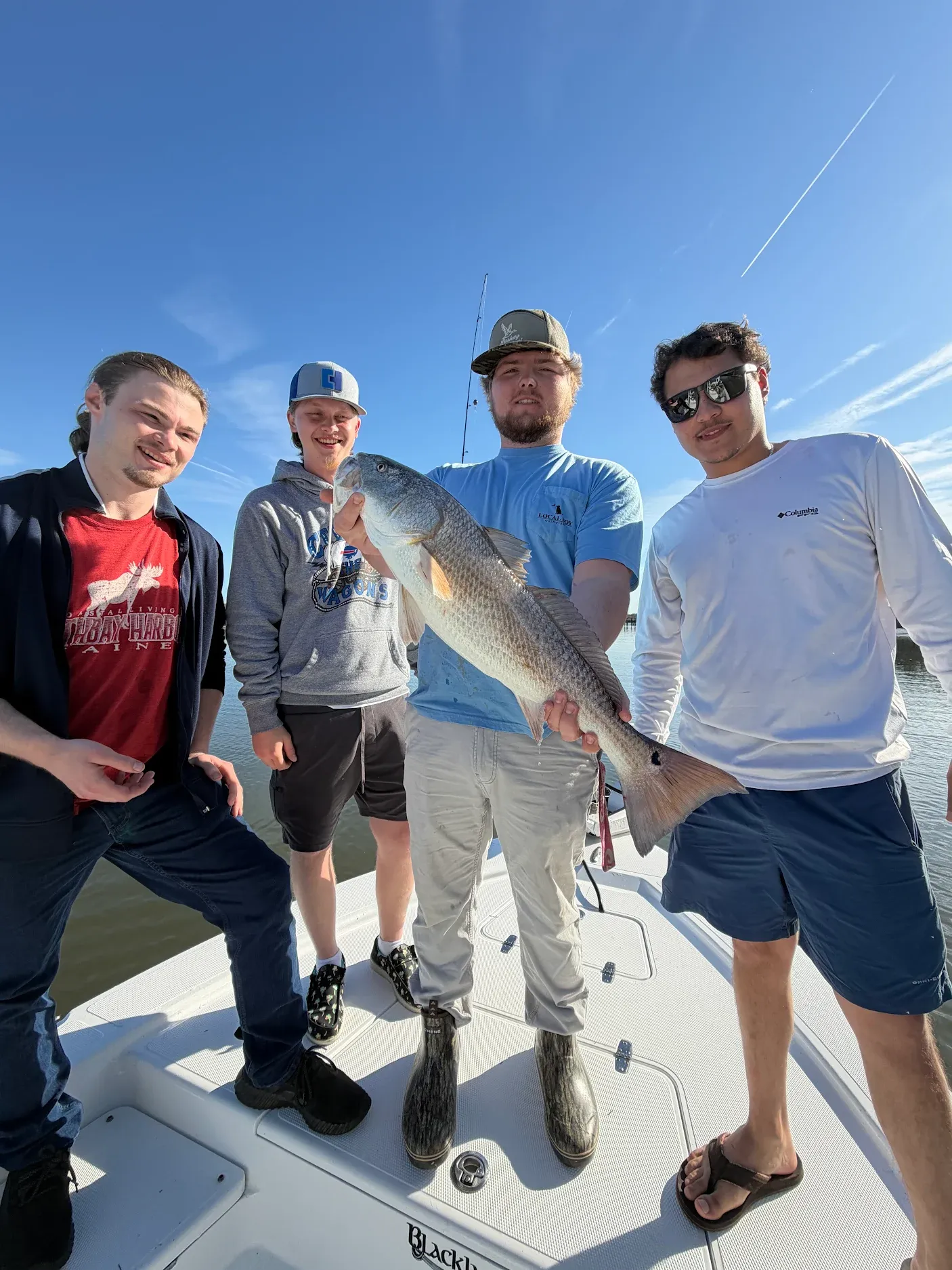 Four anglers on boat displaying caught redfish during fishing trip