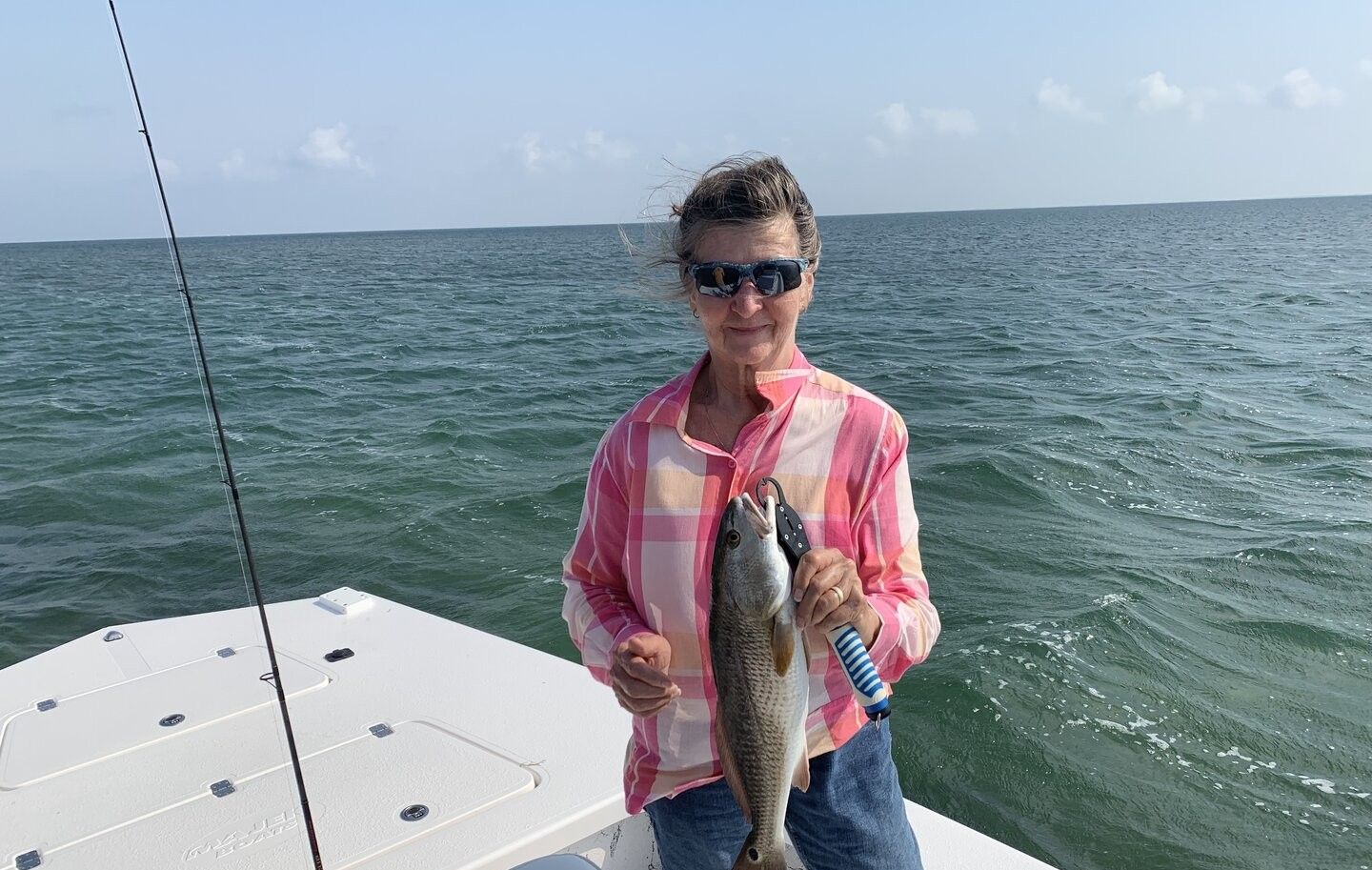 Angler holding freshly caught redfish on fishing boat in ocean waters