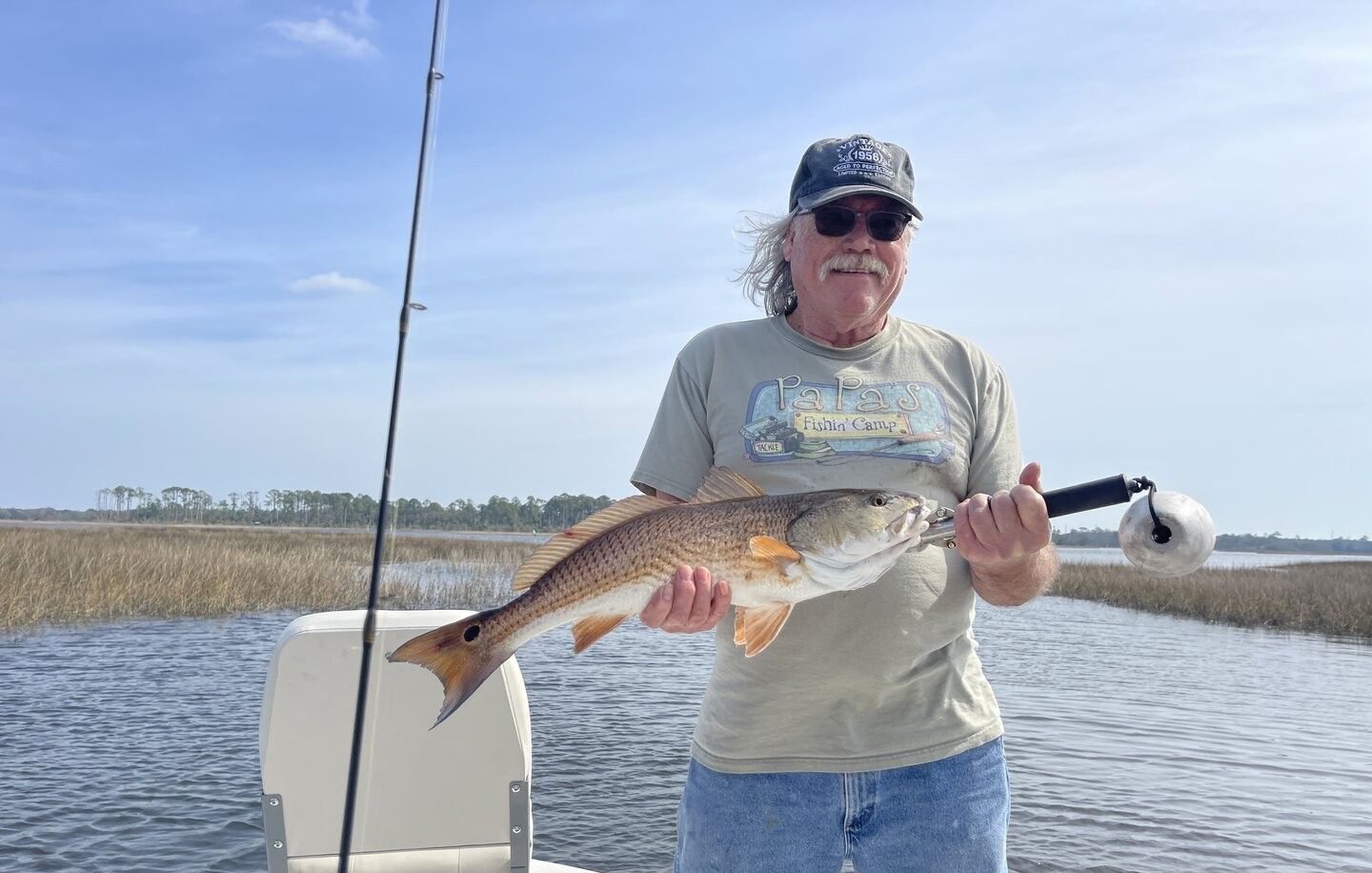 Angler holding freshly caught redfish on fishing boat in coastal waters