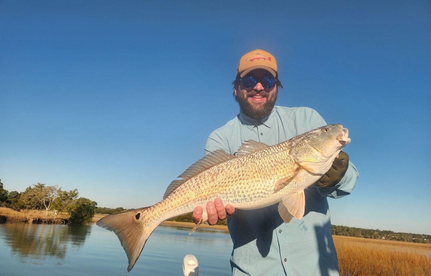 Angler holding caught redfish on fishing boat in calm waters