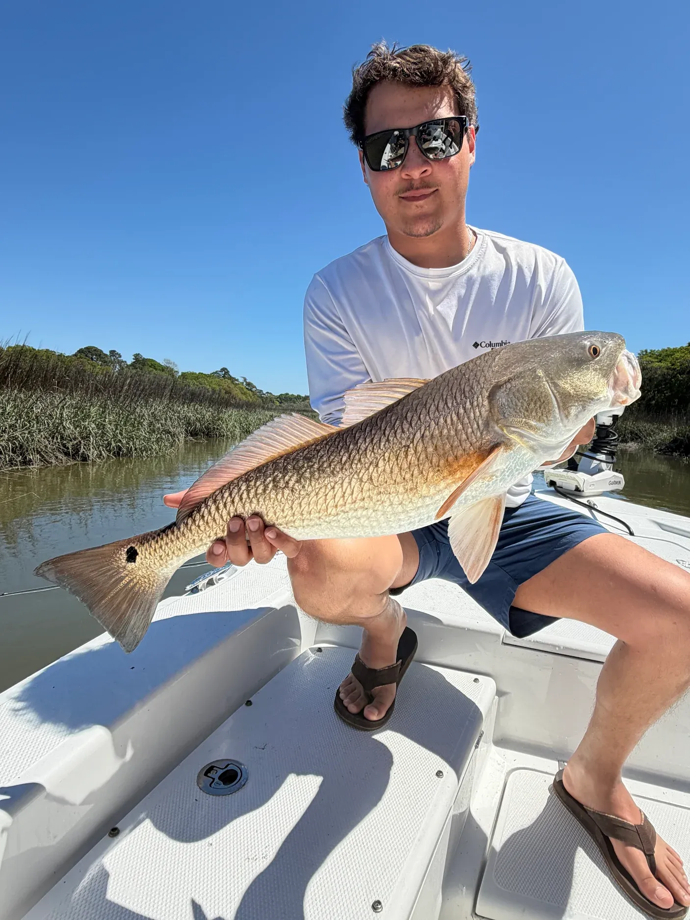 Angler holding caught redfish on fishing boat in coastal waters