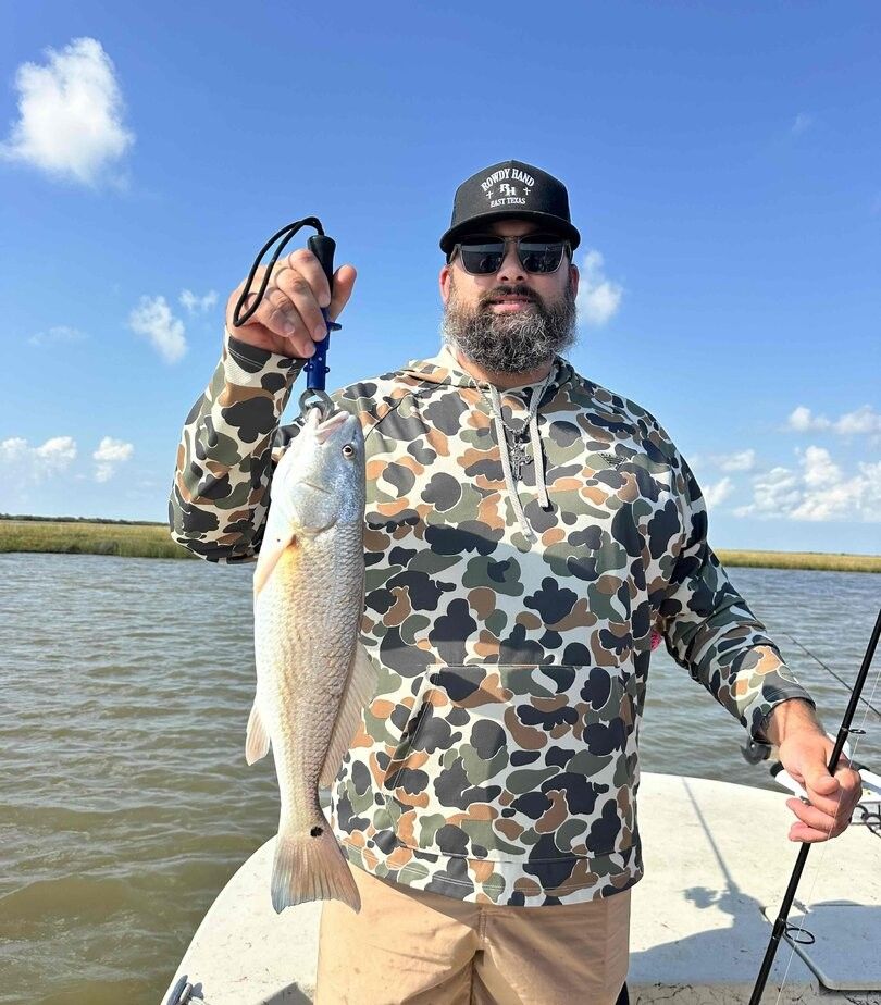 Angler holding caught redfish on boat during fishing trip