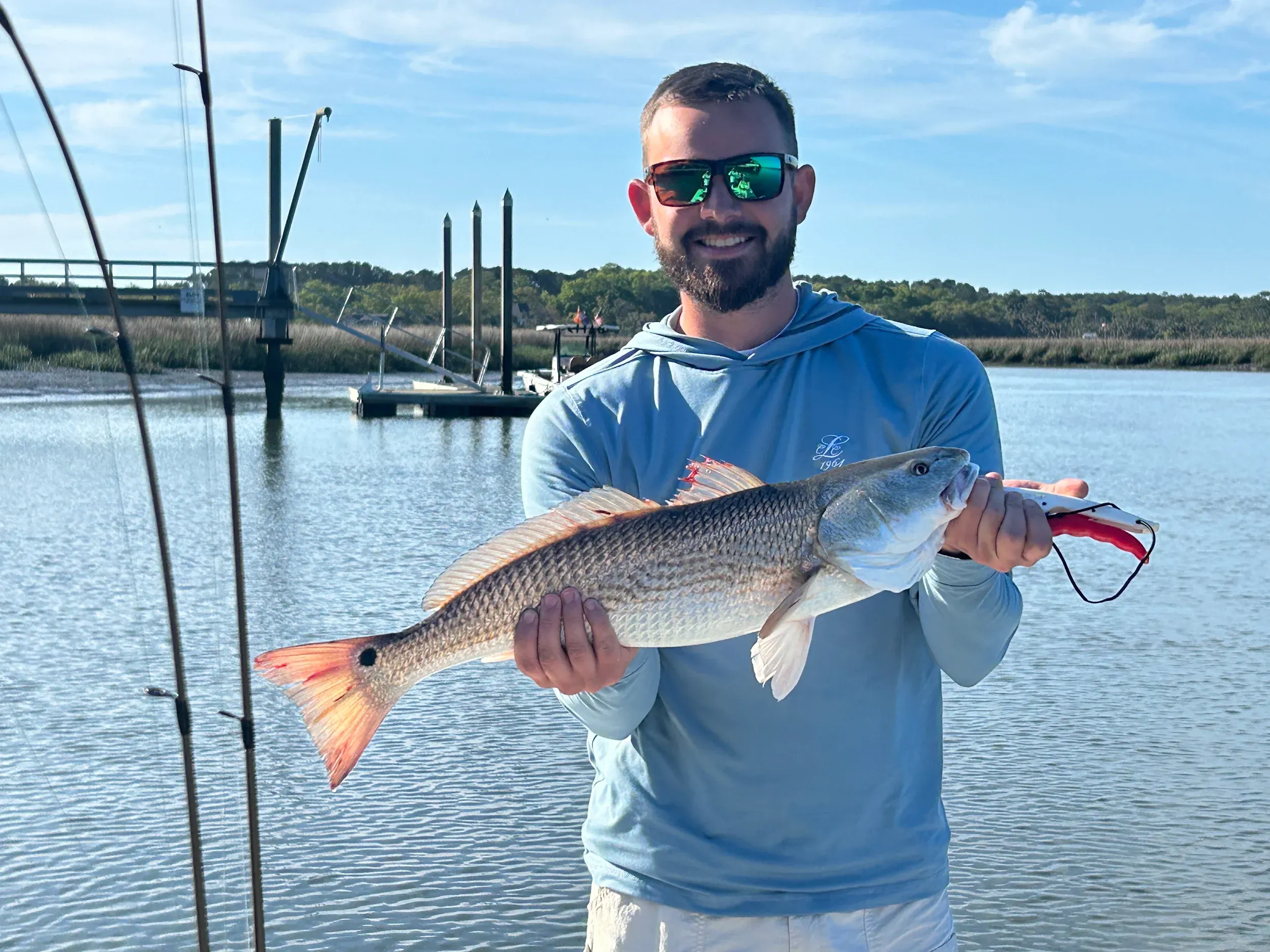 Angler holding caught redfish on fishing boat in coastal waters