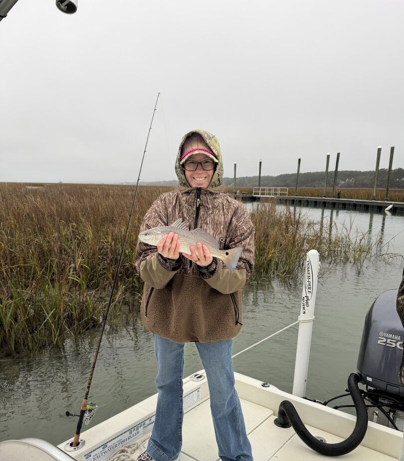 Angler holding caught redfish on fishing boat in marsh waters