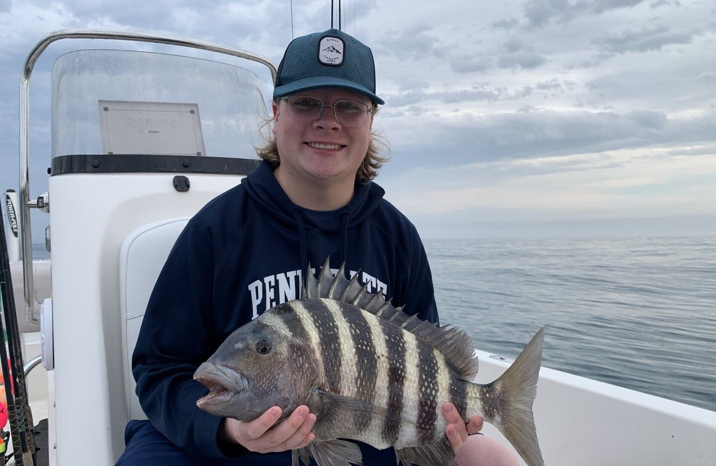 Freshly caught sheepshead fish being held on fishing boat deck over ocean water