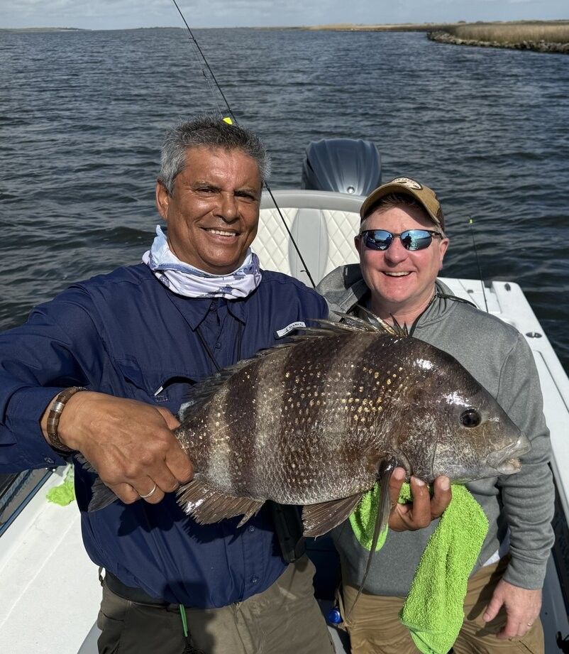 Two anglers holding a caught sheepshead fish on a fishing boat