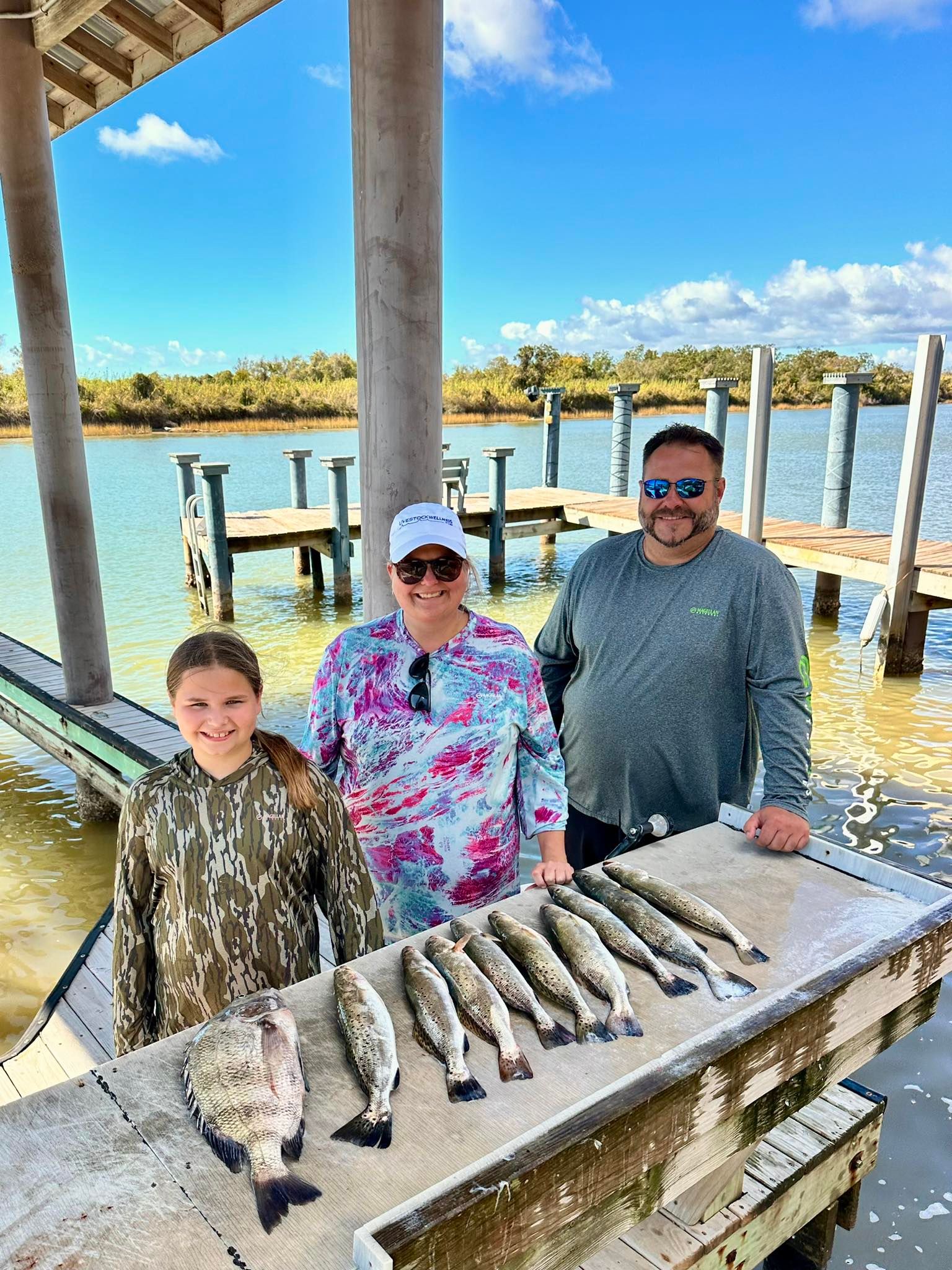 Family fishing trip displaying fresh caught sheepshead and speckled trout on cleaning table at marina dock