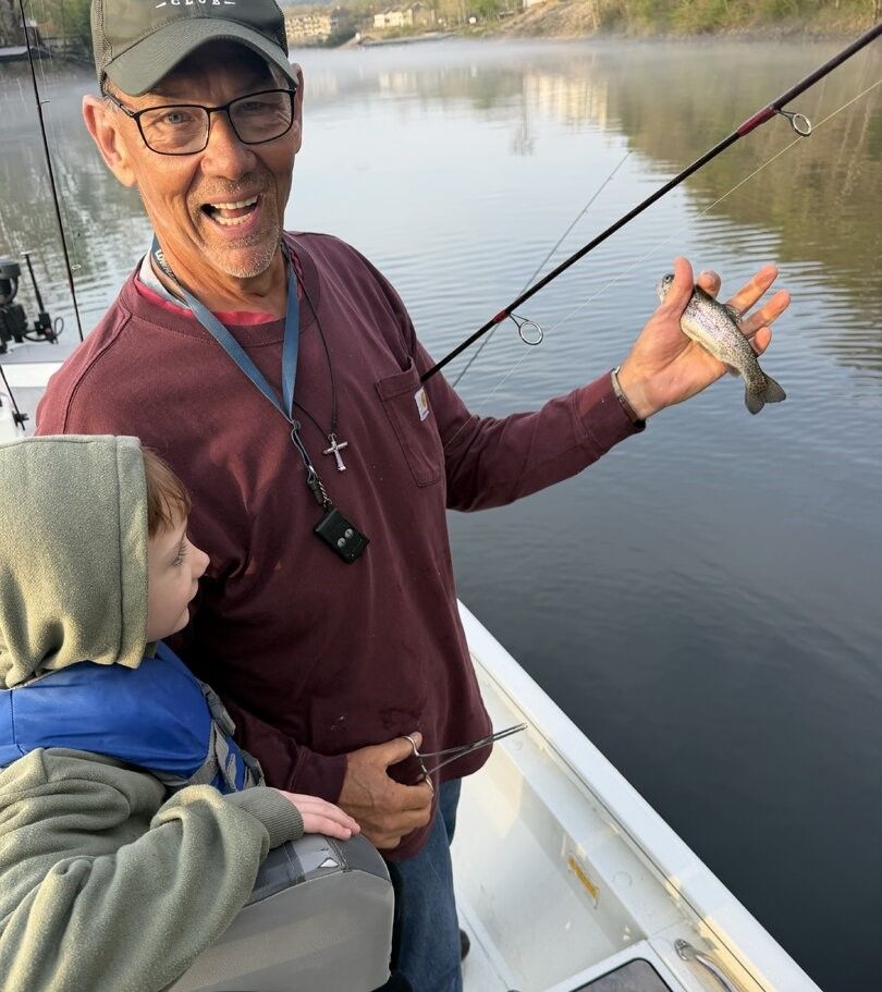 Small fish being held on fishing boat with calm water in background