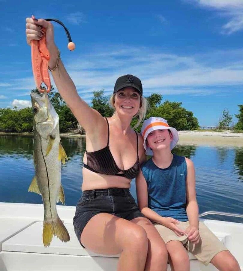A snook fish being caught by two people while fishing