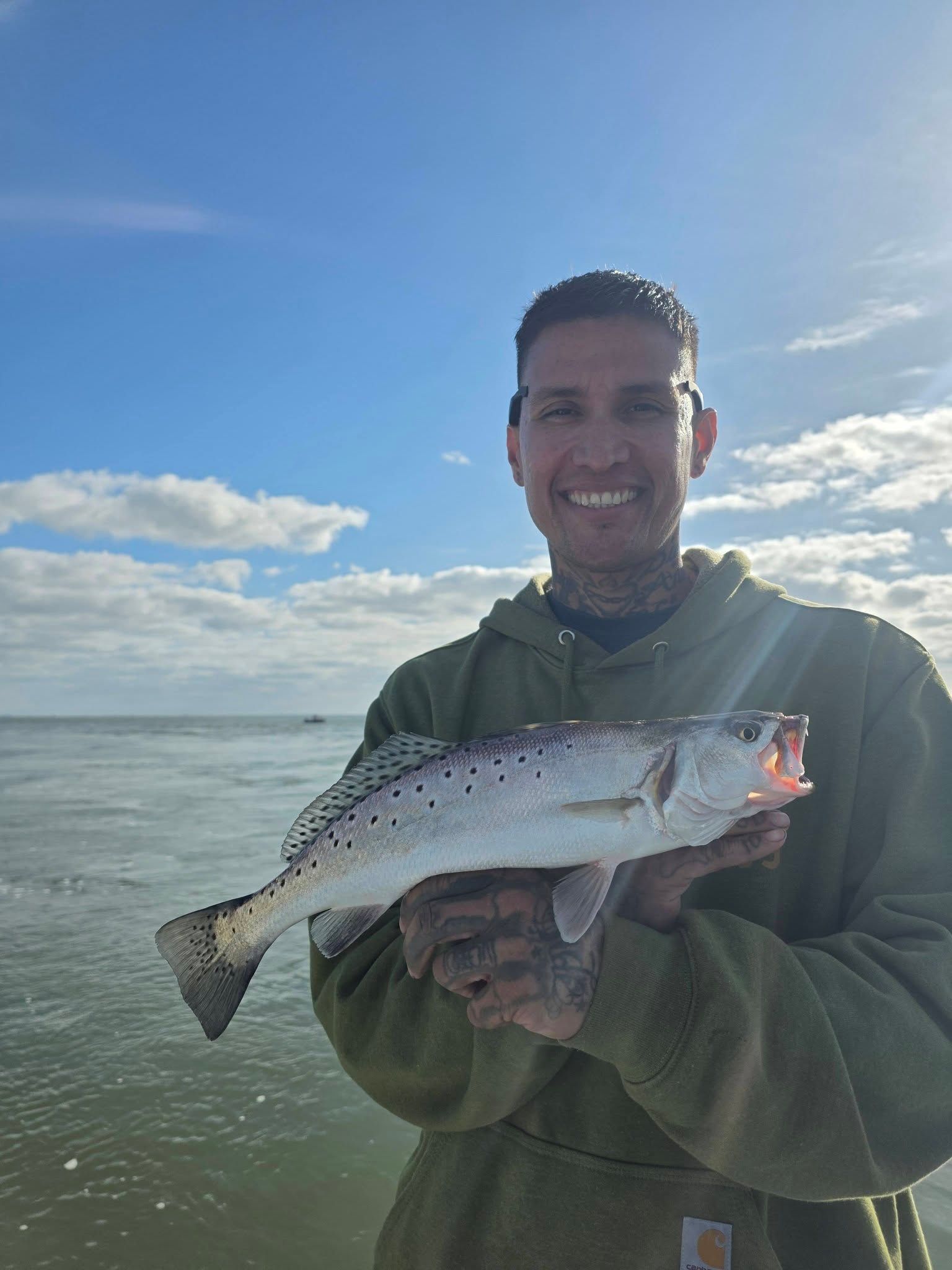 Angler holding caught speckled trout with spotted pattern on coastal waters