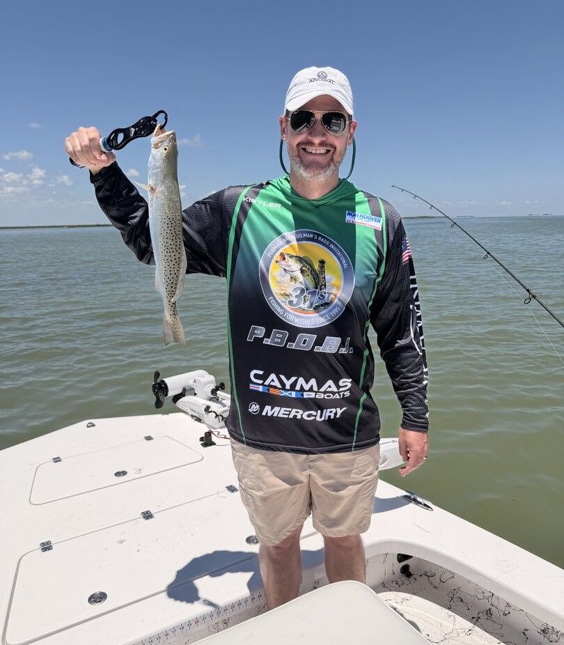 Angler holding freshly caught speckled trout on fishing boat