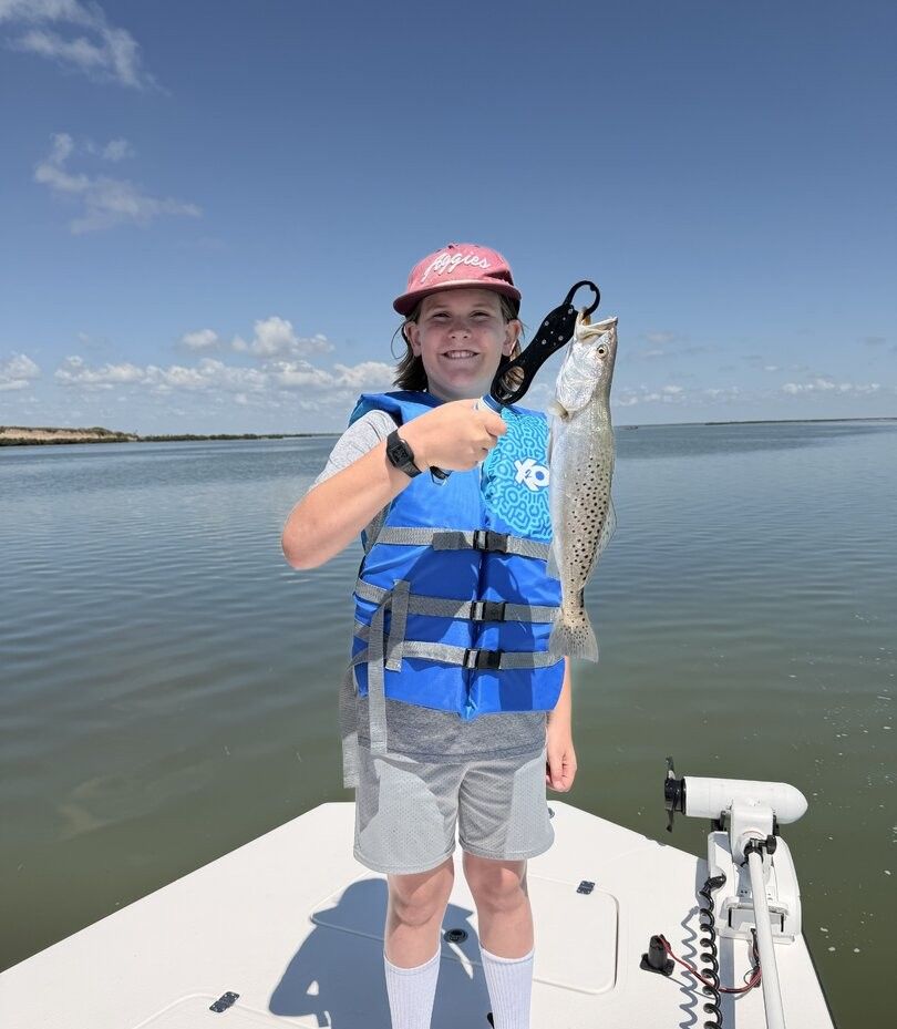 Angler holding freshly caught speckled trout on fishing boat