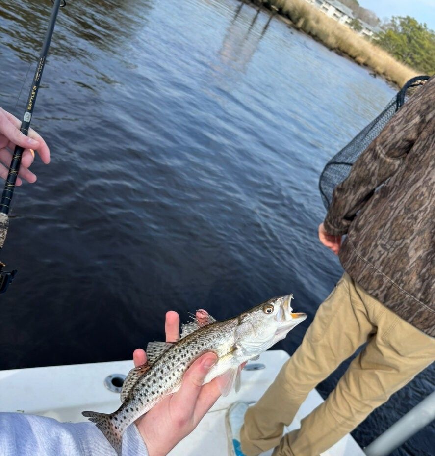 Speckled trout being held on fishing boat over water