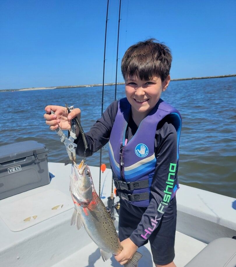 Freshly caught speckled trout being held up on fishing boat