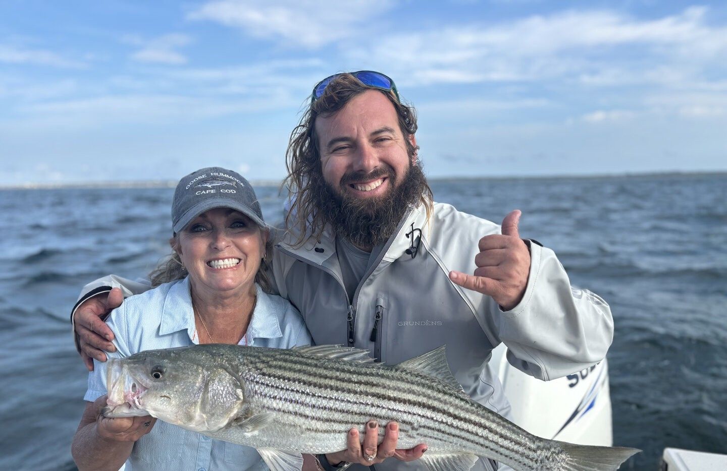 Successful striped bass fishing catch displayed on boat with ocean in background