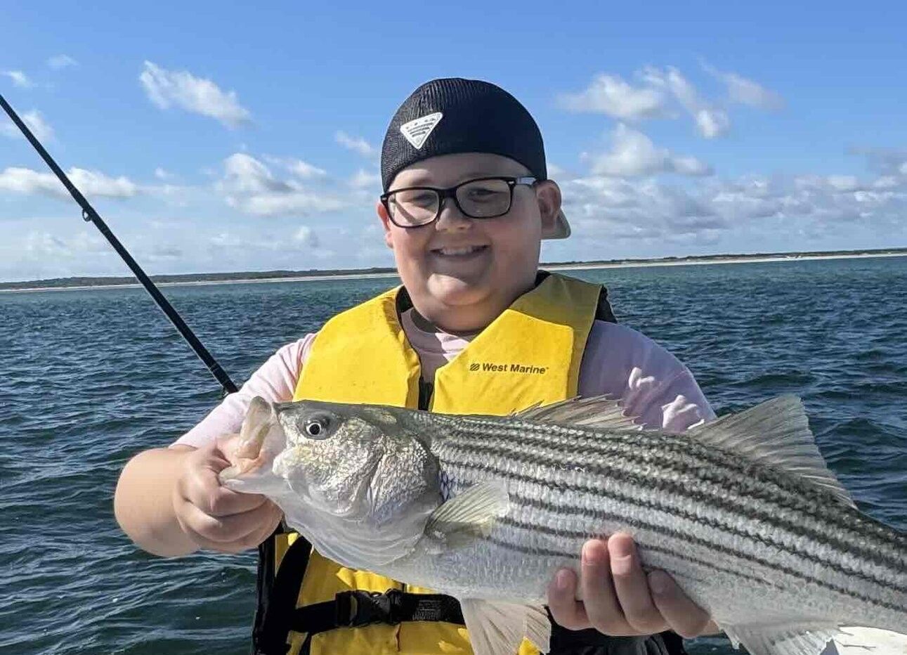 Freshly caught striped bass being held on fishing boat with ocean waters in background