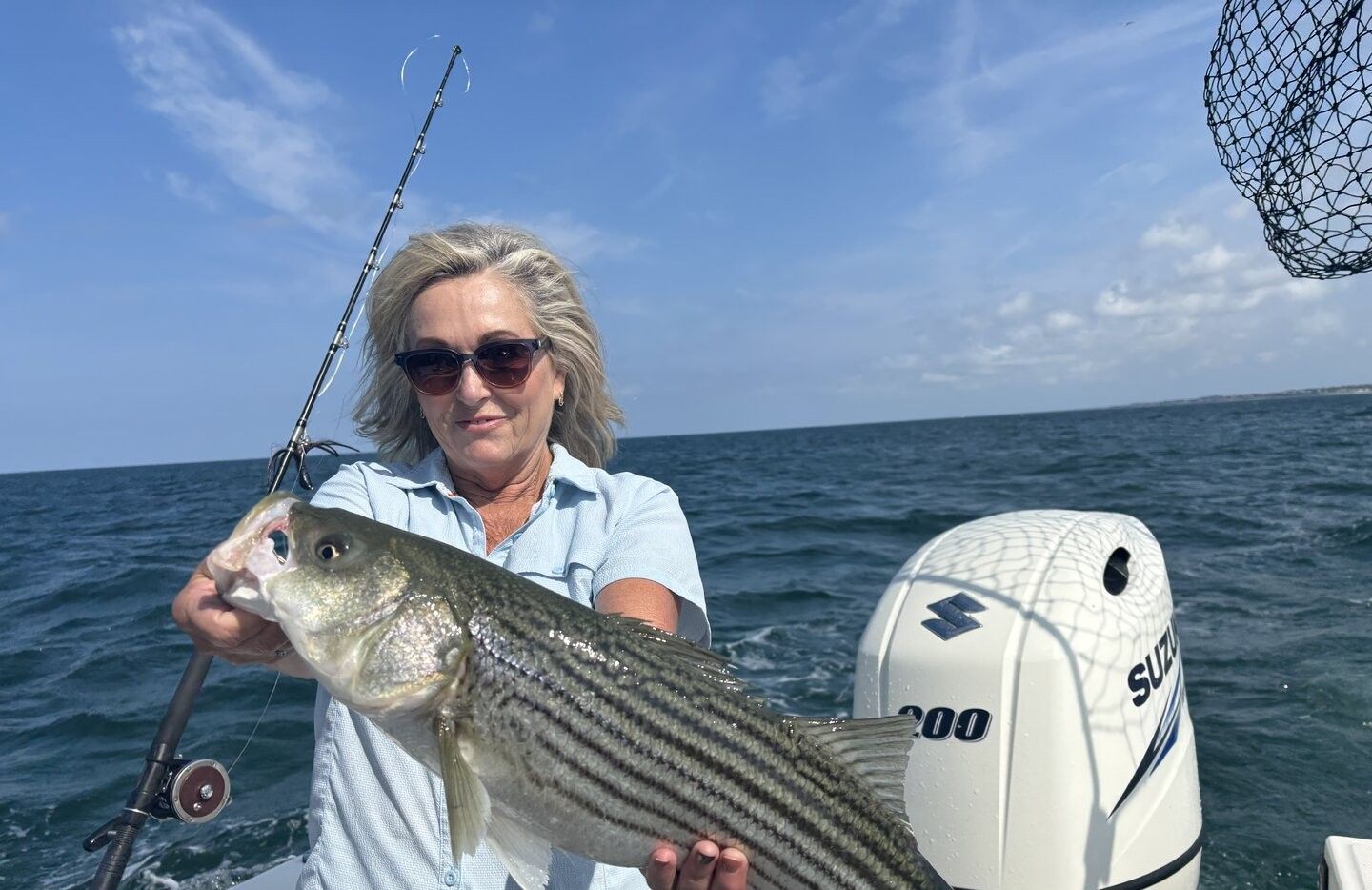 Angler holding freshly caught striped bass on fishing boat