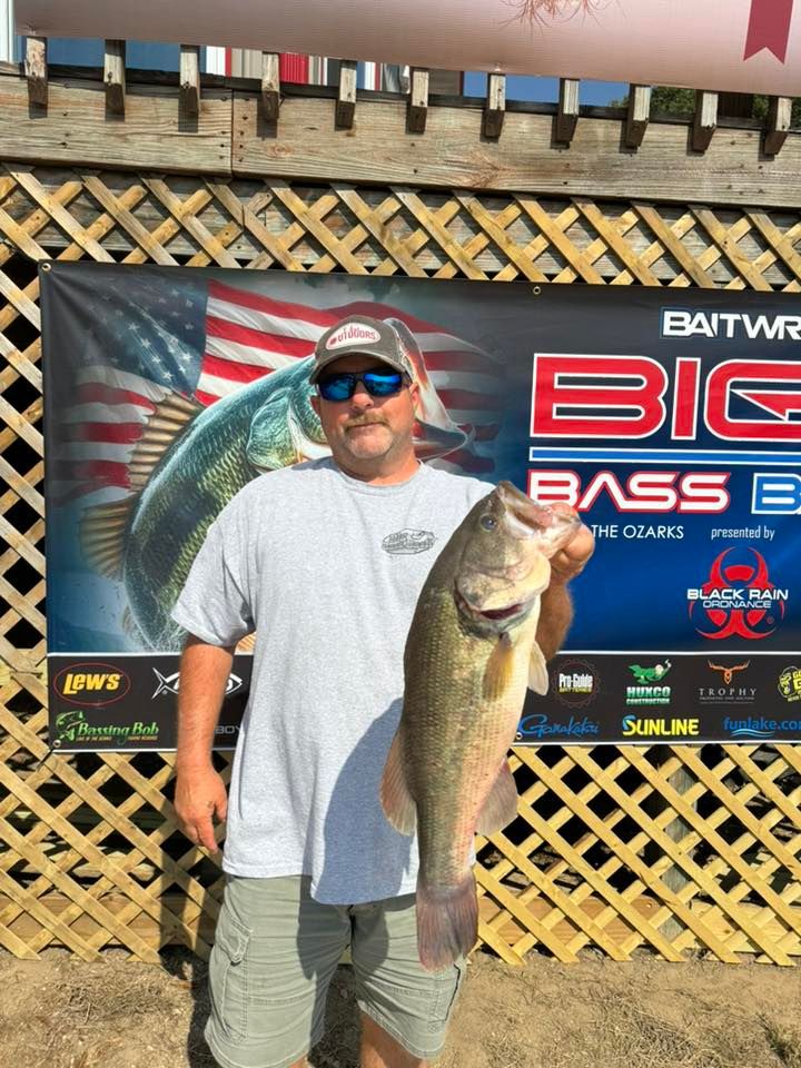 Large bass catch displayed at fishing tournament with American flag backdrop