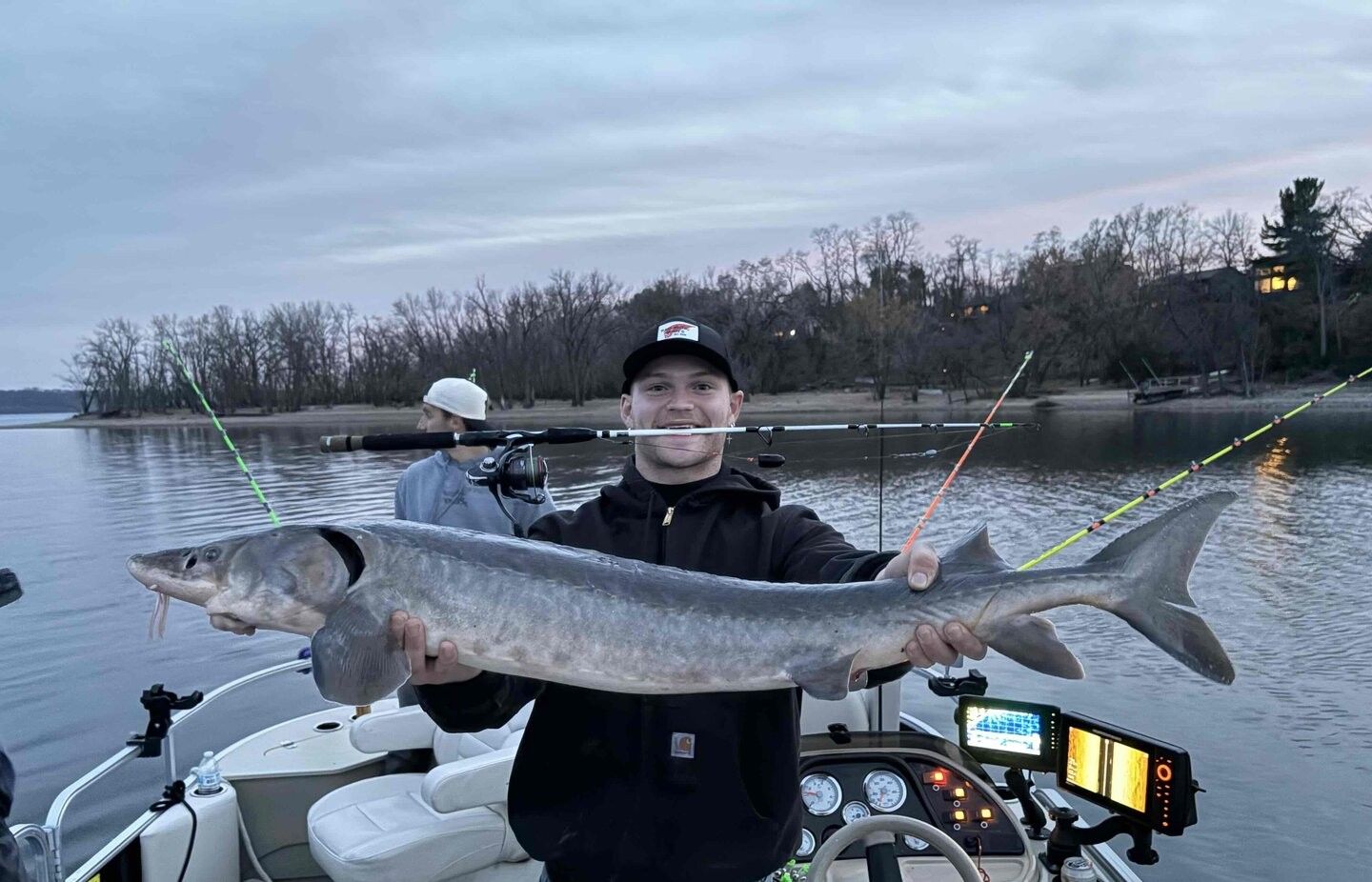 Lake sturgeon catch displayed on fishing boat with multiple fishing rods and electronic equipment visible