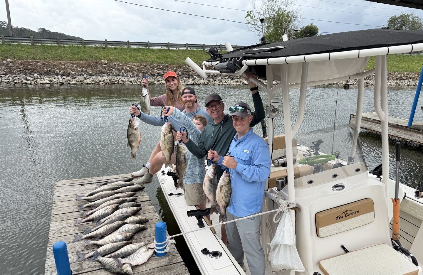 Successful fishing trip with white bass and striped bass catch displayed on dock next to fishing boat