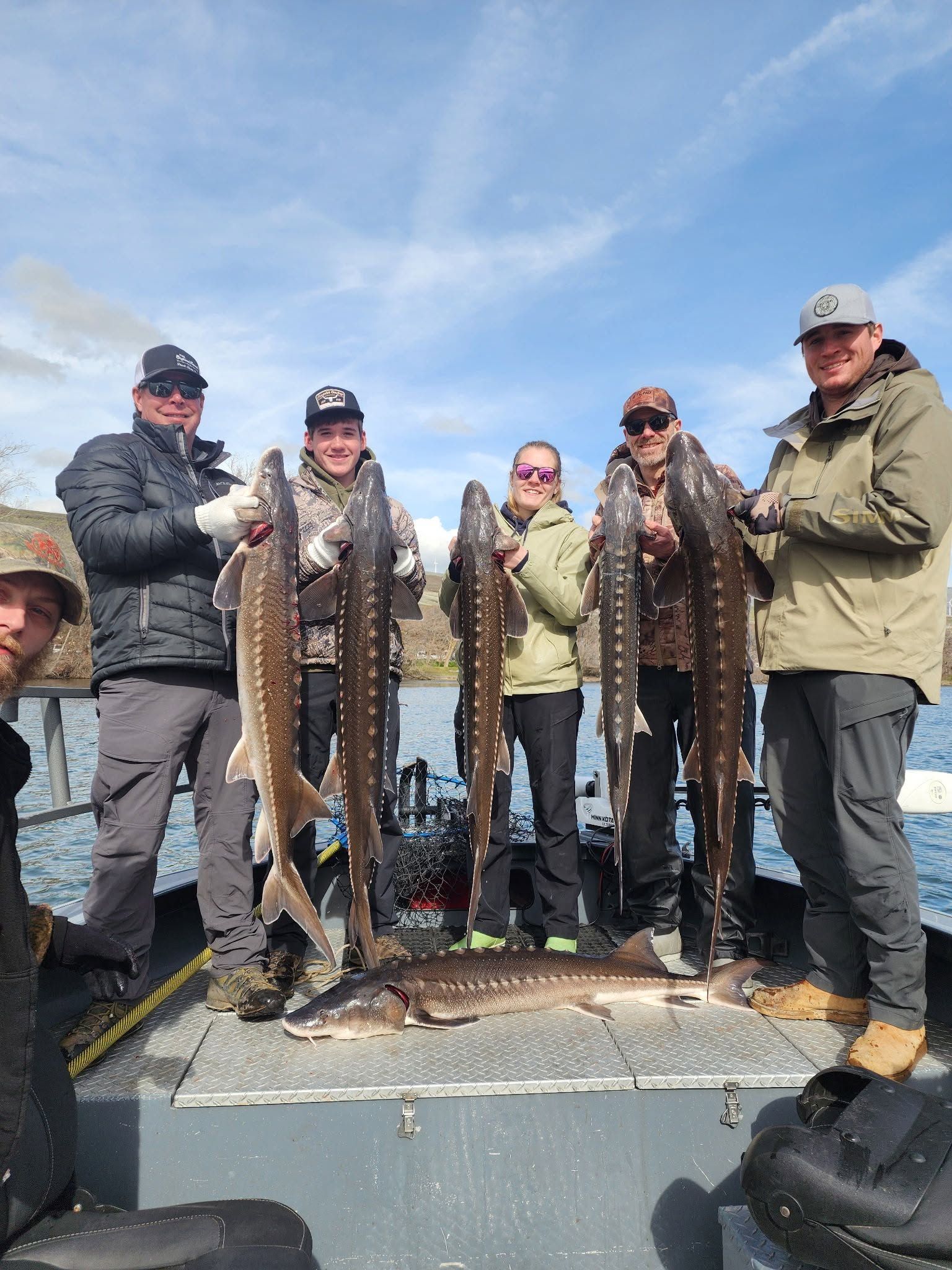 Group of anglers displaying their catch of white sturgeon on fishing boat deck