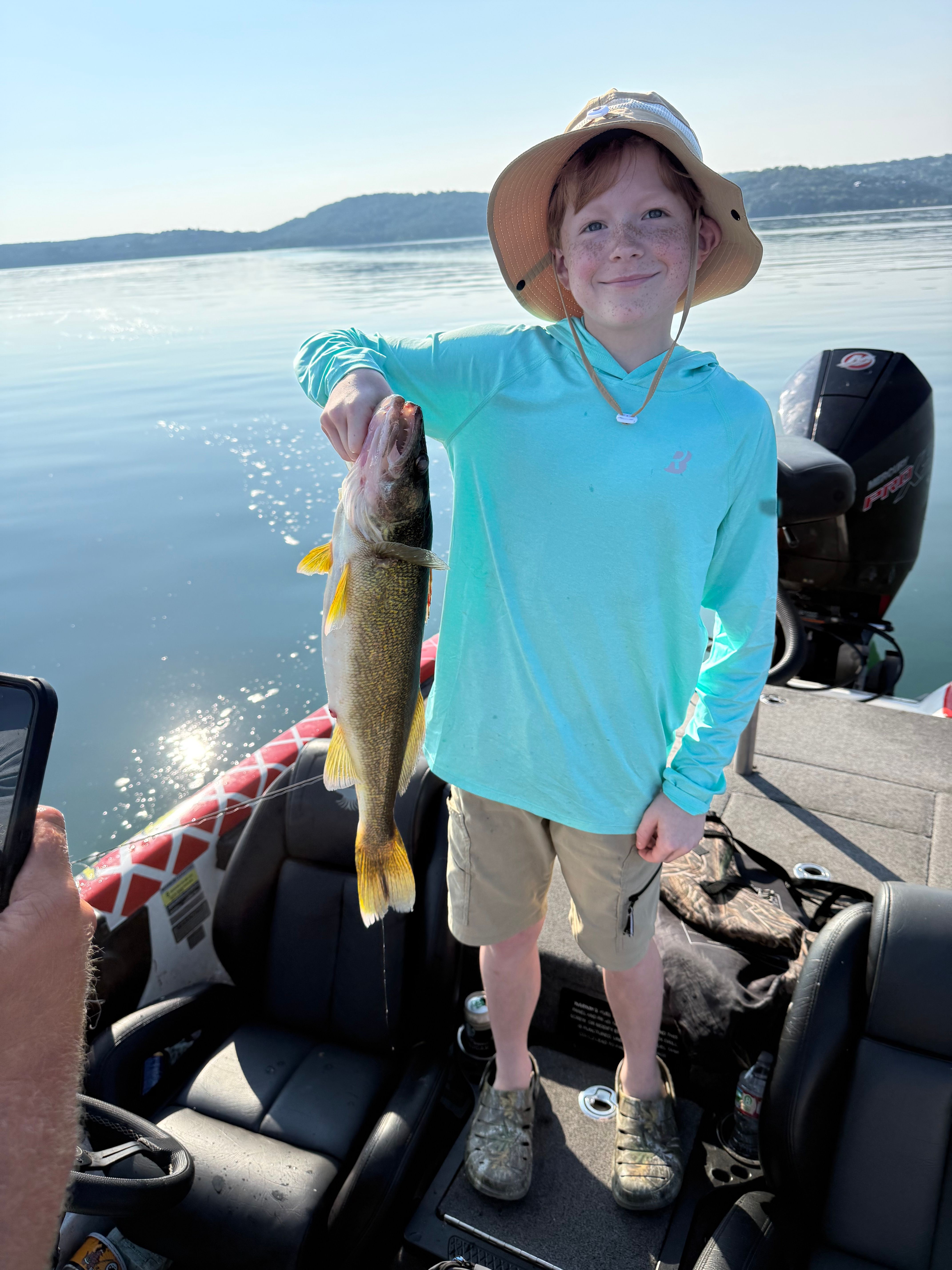 Angler holding freshly caught walleye on fishing boat