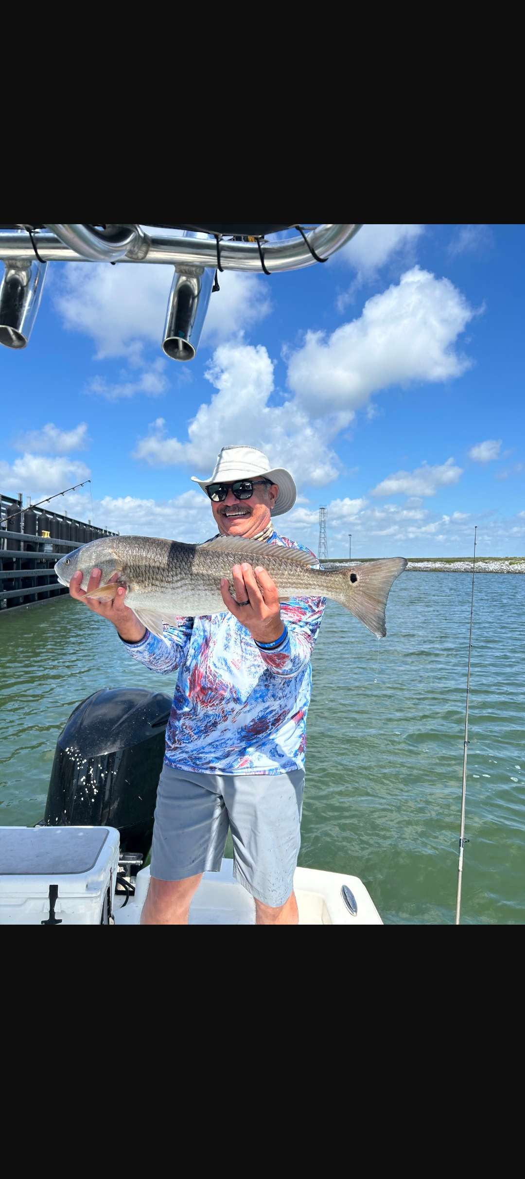 Angler holding caught redfish on boat