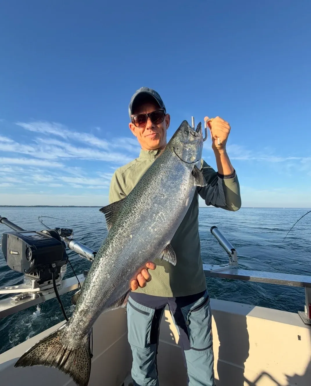 Angler holding large Chinook salmon on fishing boat in open water