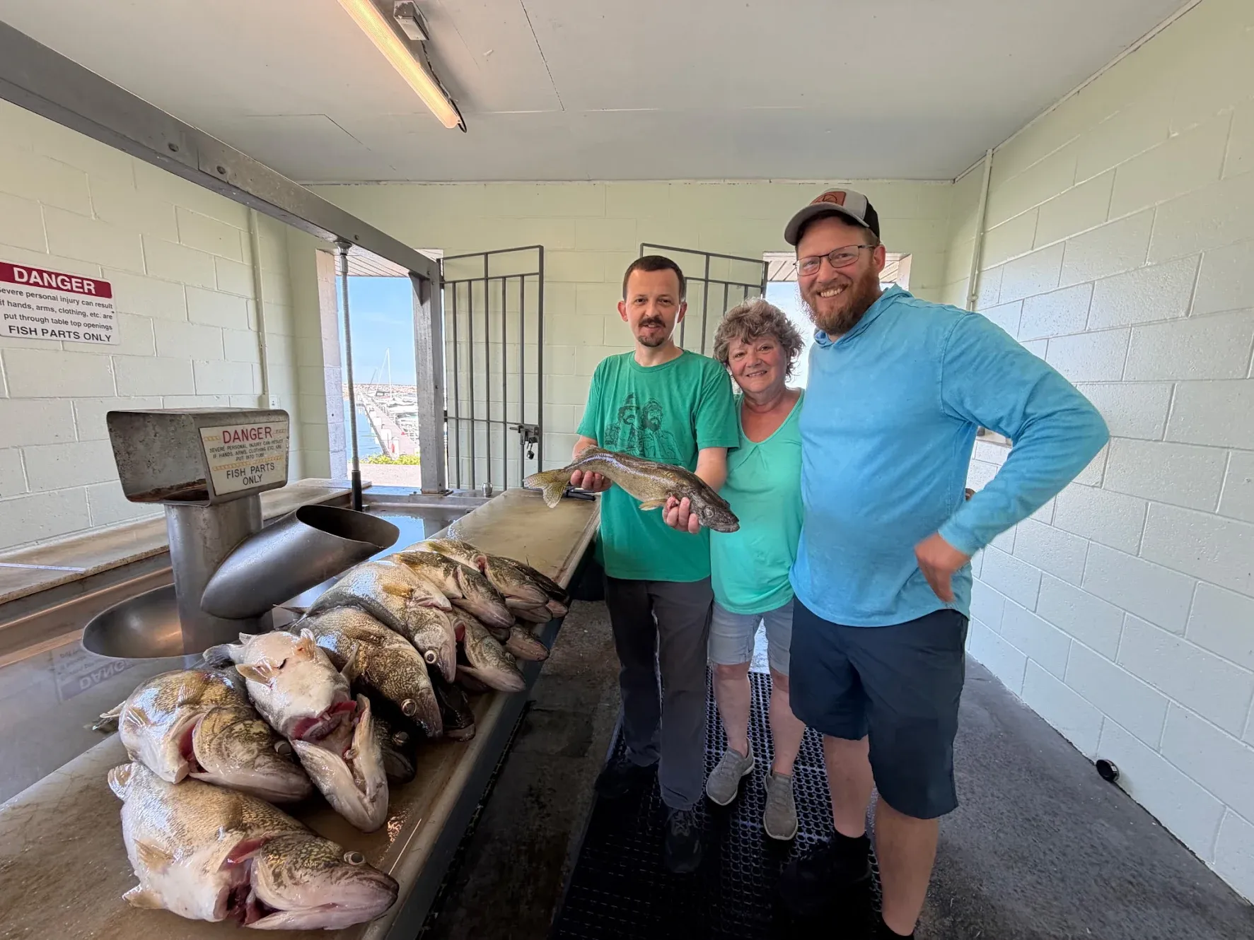 Fresh caught fish displayed on cleaning station with anglers posing at fish cleaning facility