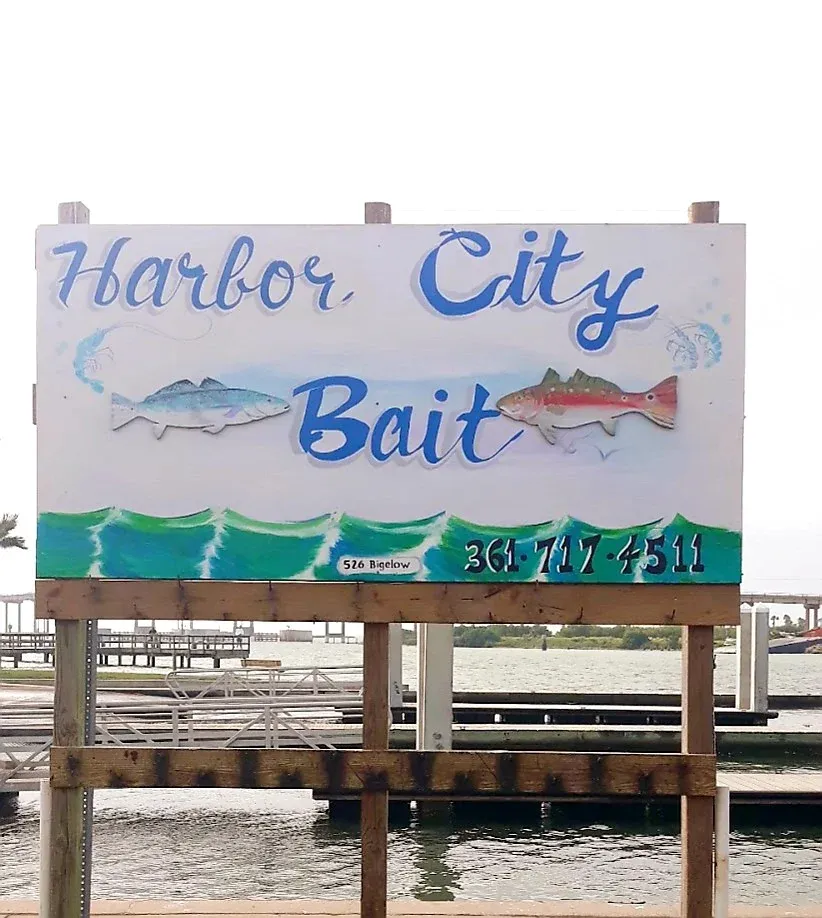 Harbor City Bait shop sign with fish illustrations and phone number displayed on wooden dock over water