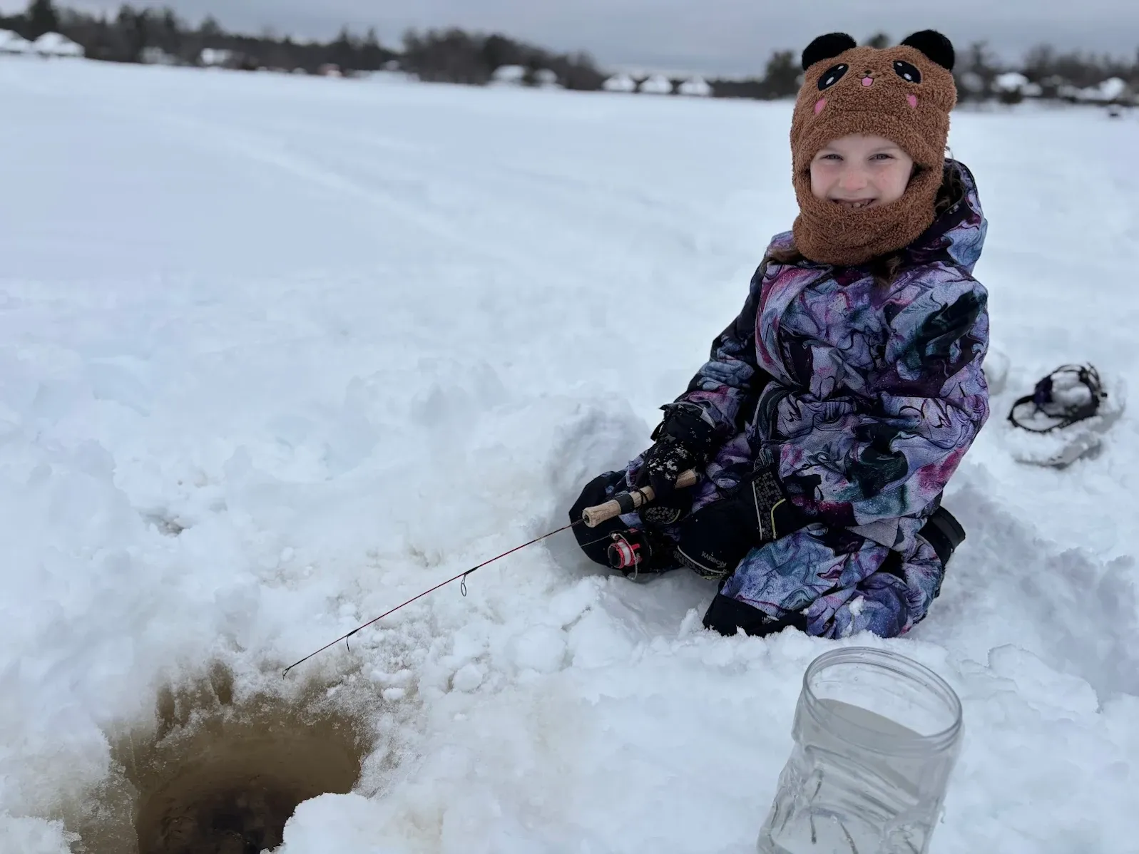 Ice fishing setup with fishing line extending into hole cut through frozen lake surface