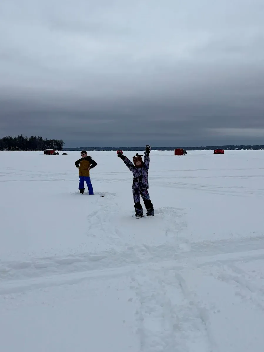 Ice fishing scene on frozen lake with ice fishing shelters in snowy winter conditions