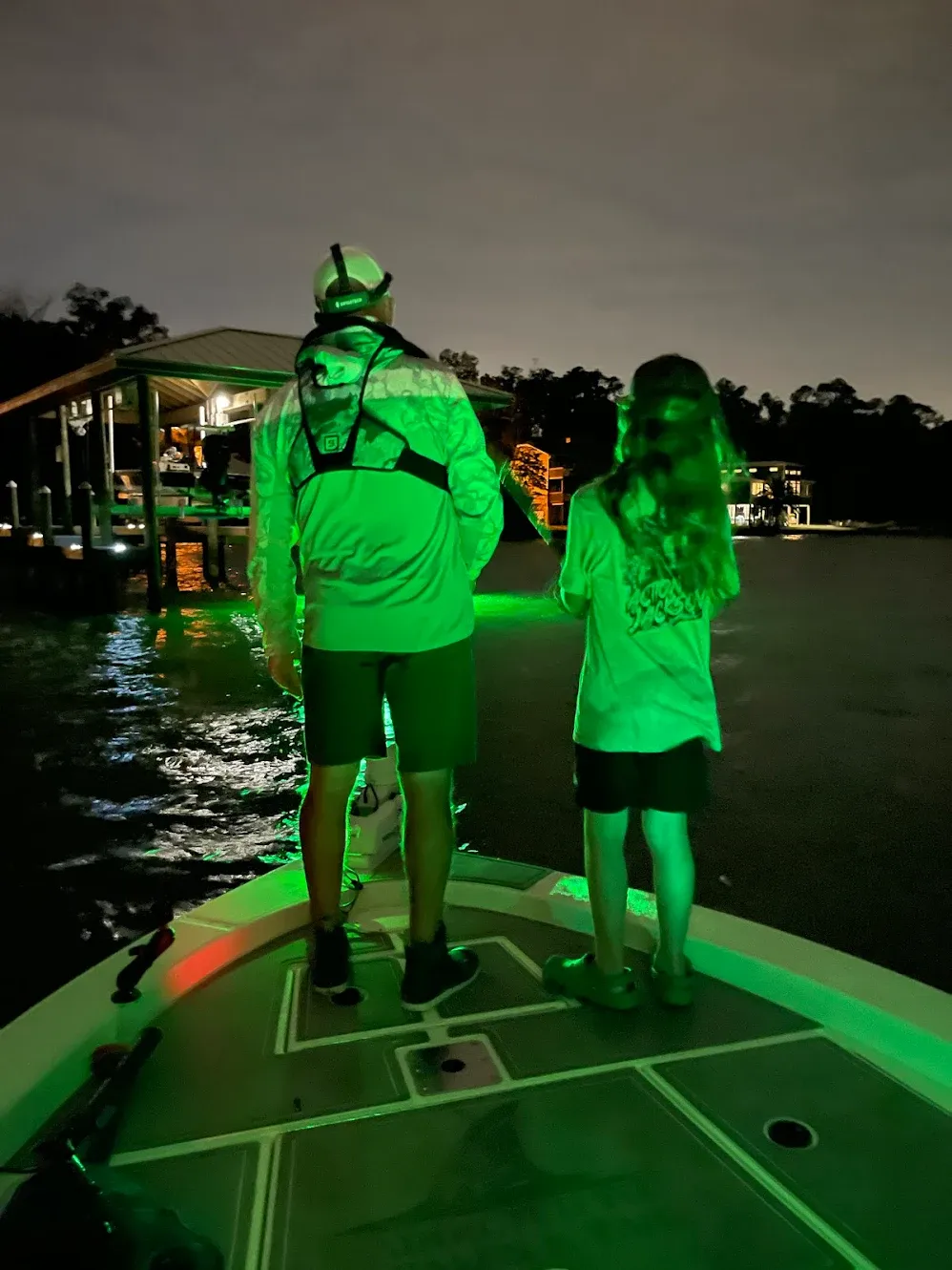 Night fishing scene with green underwater lights illuminating boat deck and water
