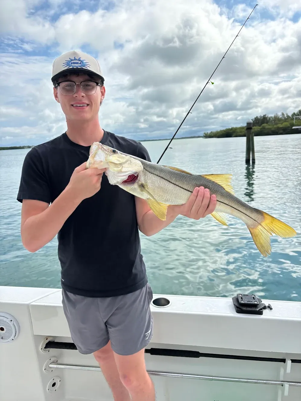 Angler holding caught snook fish on boat in coastal waters