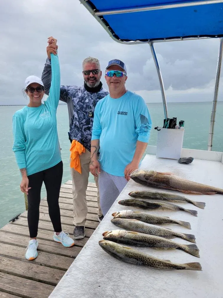 Three people fishing with three big fish in unknown location