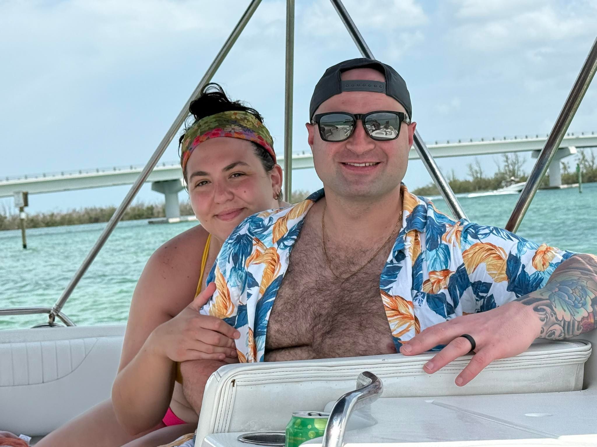 Couple enjoying a boat cruise on turquoise waters with bridge in background