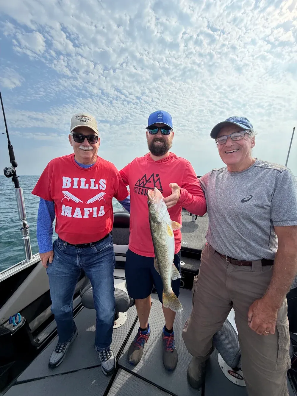 Three anglers on fishing boat displaying caught walleye