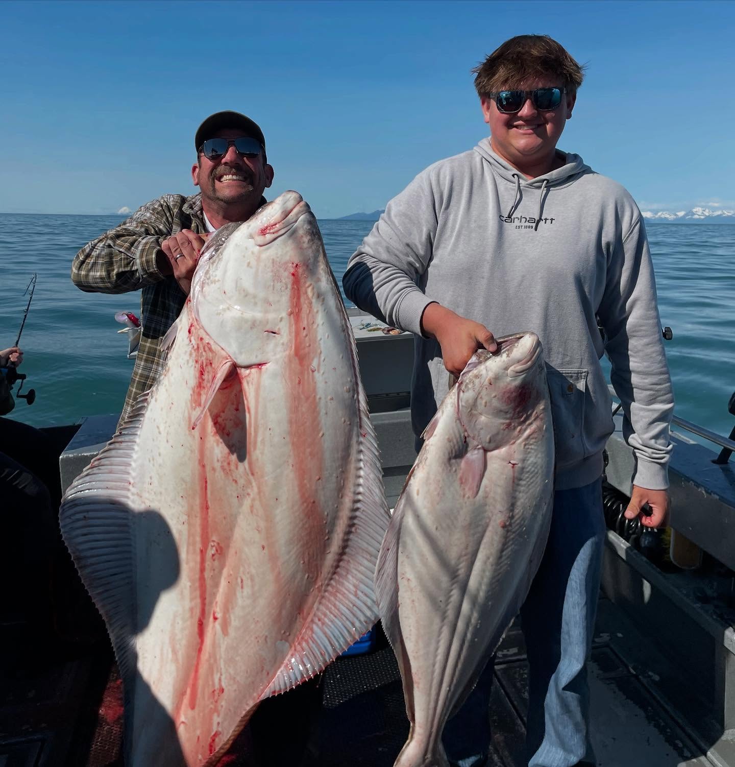 Two anglers holding Pacific Halibut caught while fishing in Homer, Alaska