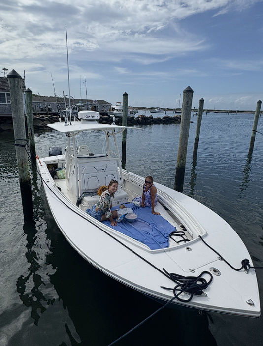 White fishing boat docked at marina in New Bedford MA with fishing equipment ready for charter