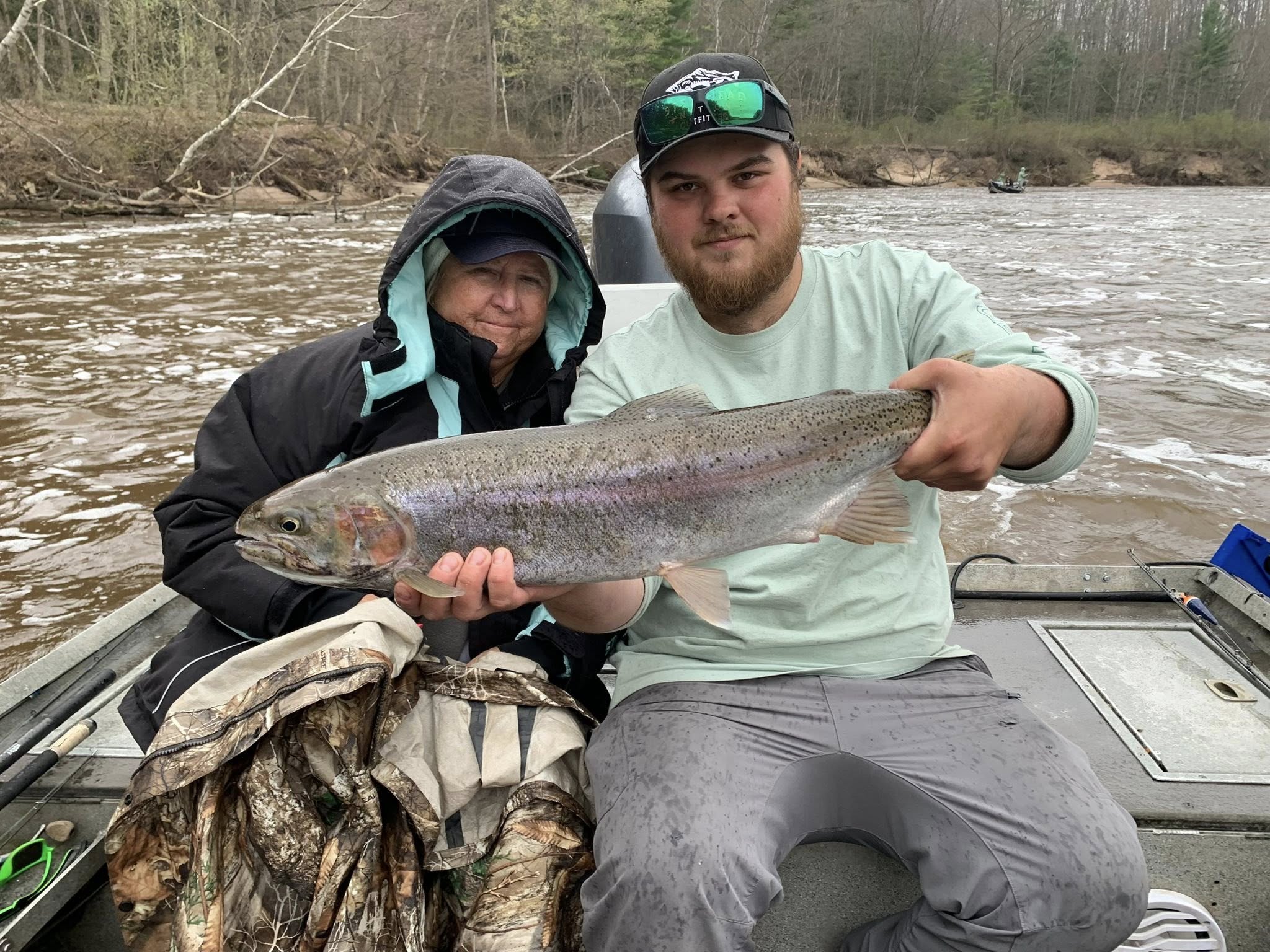 Two anglers displaying a rainbow trout catch on boat in Brethren MI