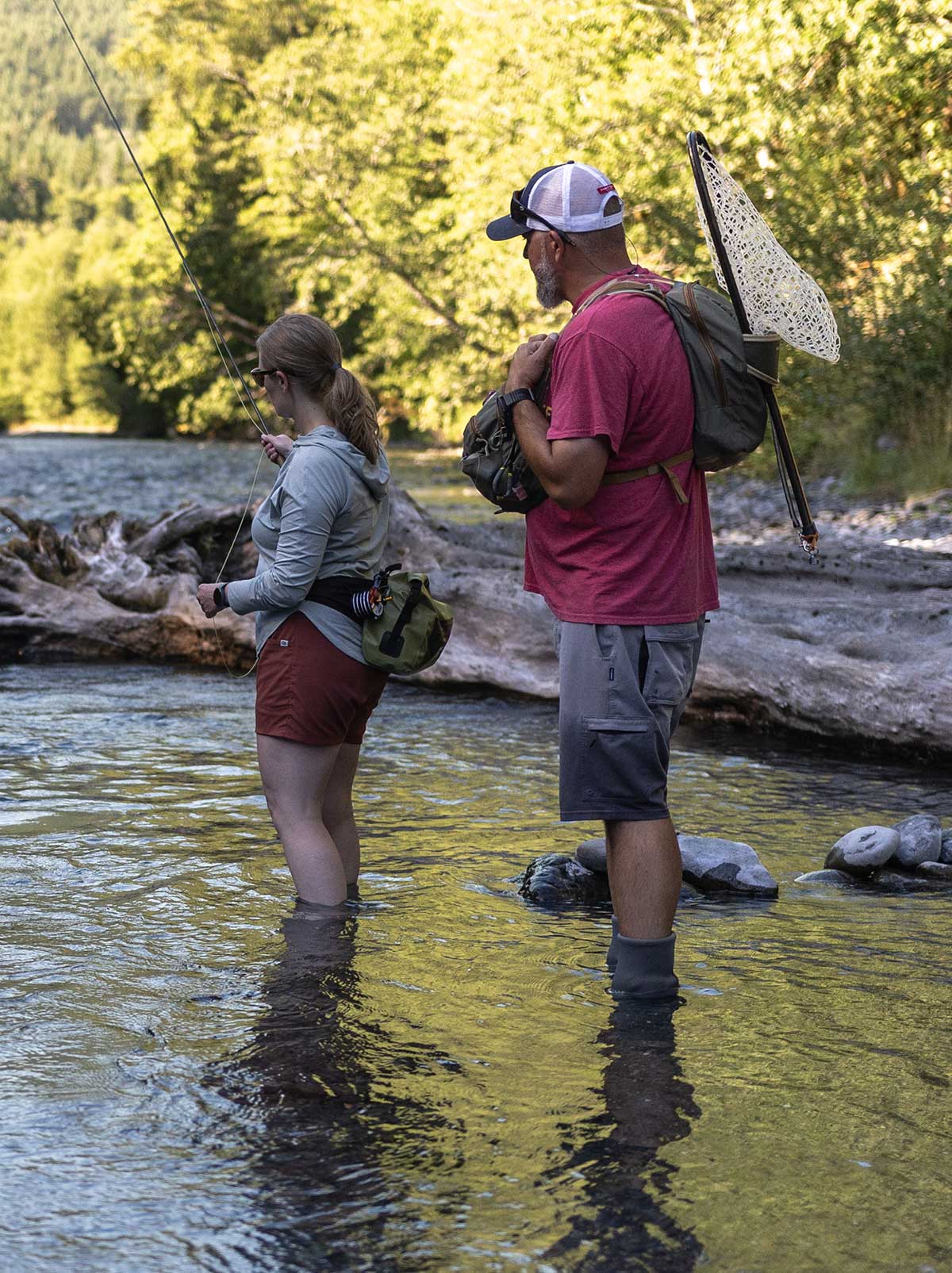 Two anglers fly fishing in clear river water near Gig Harbor Washington with fishing rods and nets