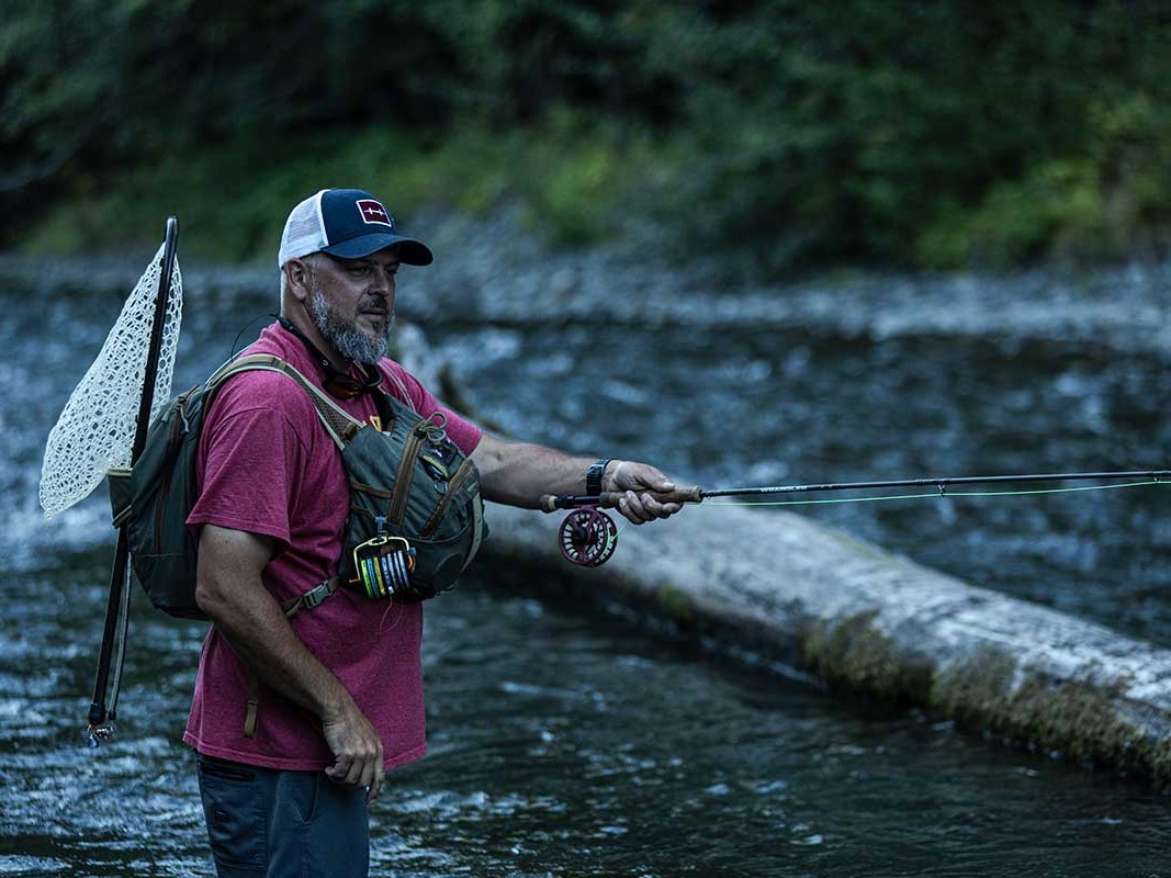 Fly fishing raft on scenic Washington lake surrounded by pine forests for trout fishing trip