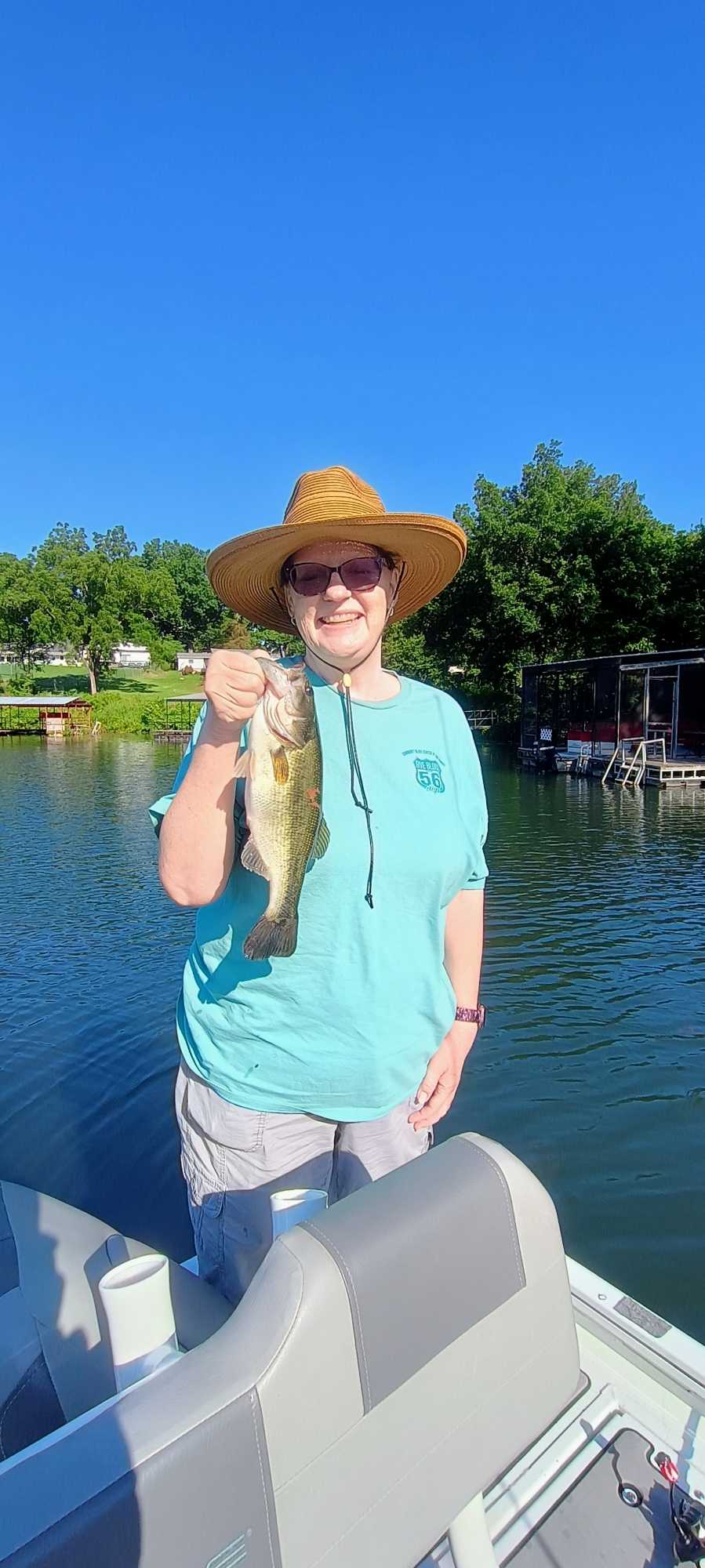 Angler holding caught bass while fishing from boat in Branson MO